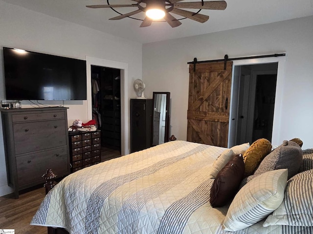 bedroom featuring wood-type flooring, a barn door, and ceiling fan