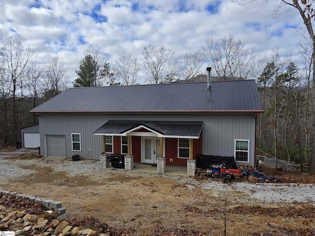 view of front of property featuring covered porch, a garage, and an outbuilding