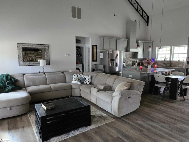 living room with washer / clothes dryer, sink, a towering ceiling, and dark wood-type flooring