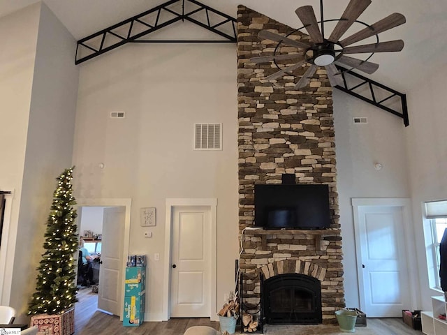 living room with a fireplace, wood-type flooring, and a high ceiling