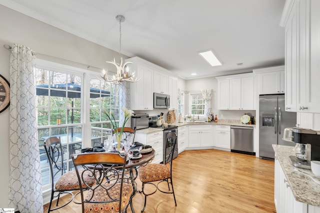 kitchen with hanging light fixtures, light wood-type flooring, appliances with stainless steel finishes, a notable chandelier, and white cabinetry