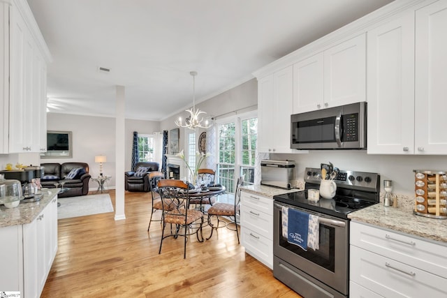 kitchen with pendant lighting, crown molding, light hardwood / wood-style flooring, white cabinetry, and stainless steel appliances