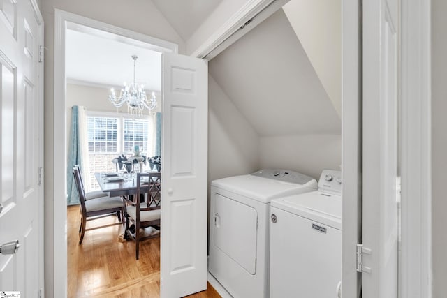 washroom featuring a chandelier, washing machine and dryer, and light hardwood / wood-style flooring