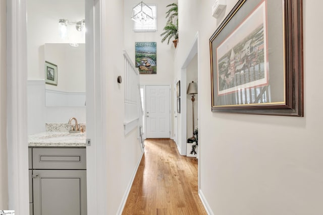 hall with light hardwood / wood-style floors and sink