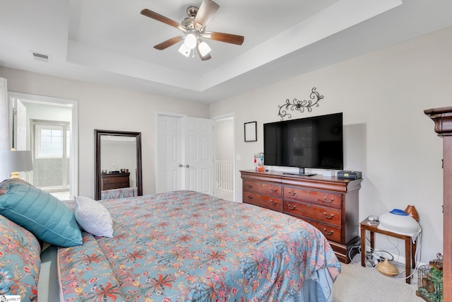 carpeted bedroom with connected bathroom, a raised ceiling, and ceiling fan