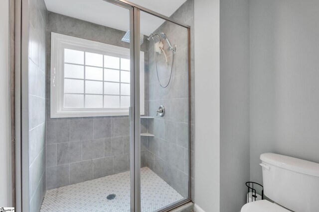 bathroom with a shower with door and toilet