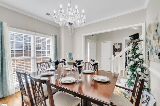 dining space featuring light wood-type flooring, crown molding, and an inviting chandelier