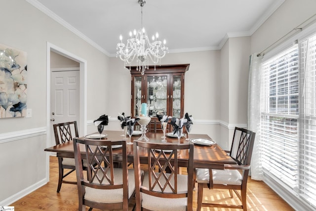 dining space with light hardwood / wood-style floors, an inviting chandelier, and ornamental molding