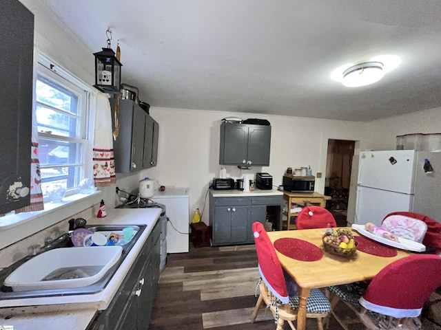 kitchen with sink, dark wood-type flooring, washer / clothes dryer, white fridge, and gray cabinets