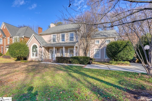 colonial home with covered porch and a front lawn