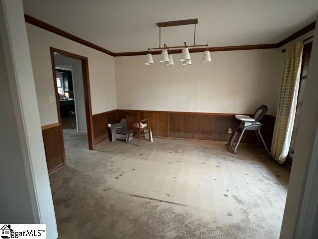 unfurnished dining area featuring wood walls and crown molding