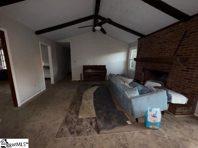 living room featuring vaulted ceiling with beams, ceiling fan, and a brick fireplace