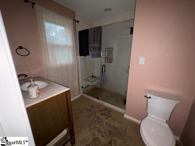 bathroom featuring vanity, toilet, and a shower with shower door