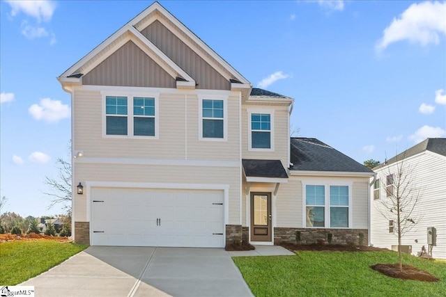 craftsman-style home featuring board and batten siding, a front yard, stone siding, and driveway