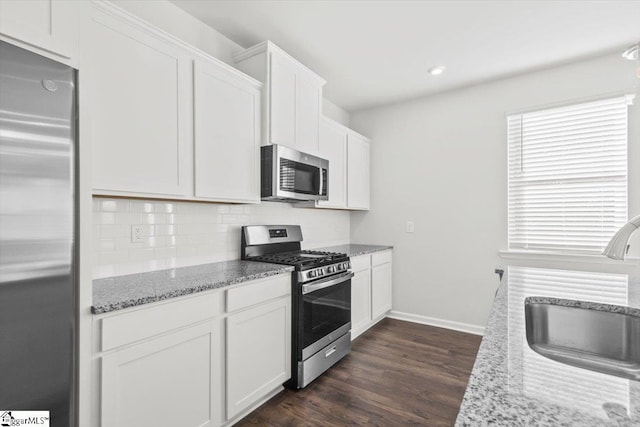 kitchen featuring white cabinets, stainless steel appliances, sink, dark hardwood / wood-style floors, and light stone counters