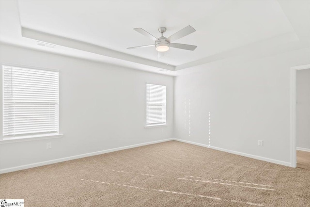 carpeted spare room featuring ceiling fan and a tray ceiling