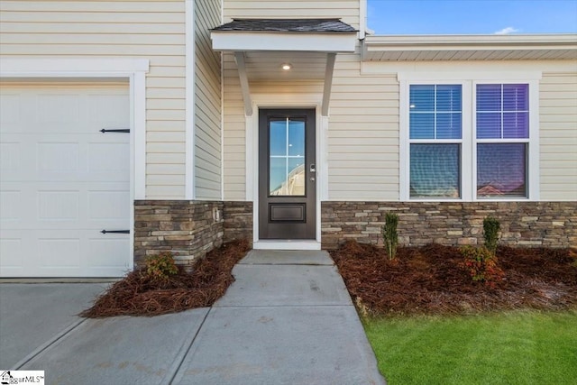 doorway to property featuring a garage and stone siding