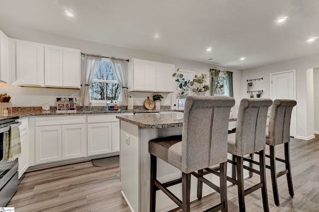 kitchen with a breakfast bar, white cabinetry, a center island, and light hardwood / wood-style floors