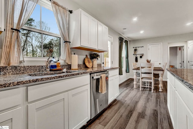 kitchen featuring sink, stainless steel dishwasher, dark stone countertops, dark hardwood / wood-style flooring, and white cabinetry