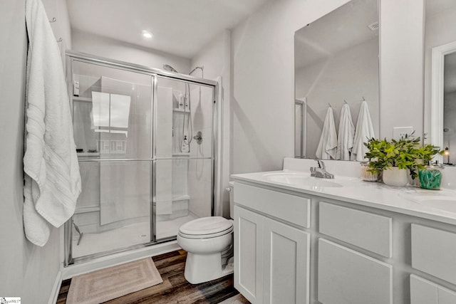 bathroom featuring vanity, hardwood / wood-style flooring, toilet, and a shower with shower door