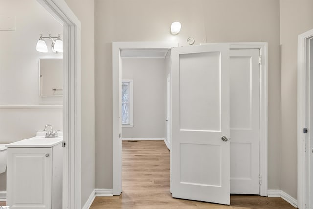 hall with light wood-type flooring and sink