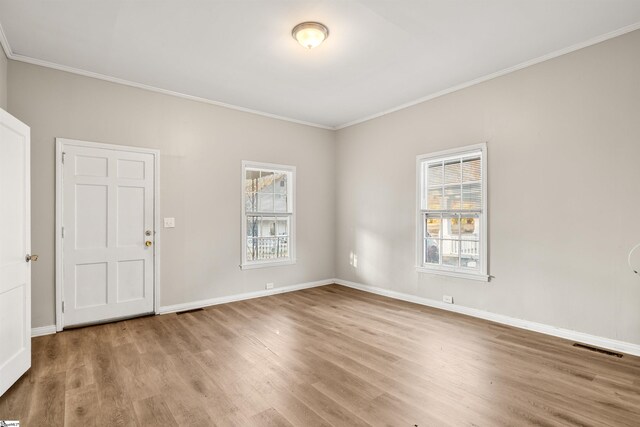 empty room with crown molding, plenty of natural light, and light hardwood / wood-style floors