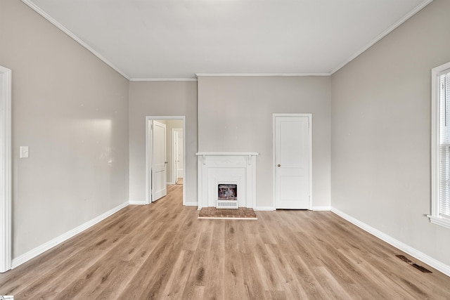 unfurnished living room featuring plenty of natural light, crown molding, and light hardwood / wood-style flooring