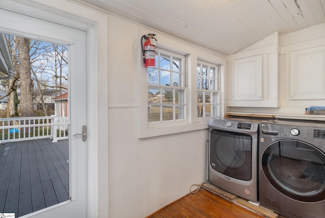 clothes washing area with separate washer and dryer, cabinets, hardwood / wood-style floors, and a healthy amount of sunlight