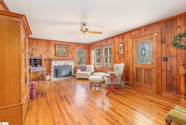 living room featuring wood walls, light hardwood / wood-style flooring, ceiling fan, and crown molding