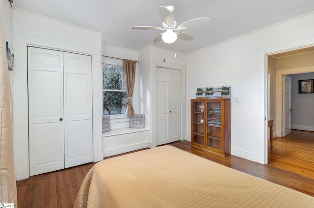 bedroom with multiple closets, ceiling fan, dark wood-type flooring, and ornamental molding