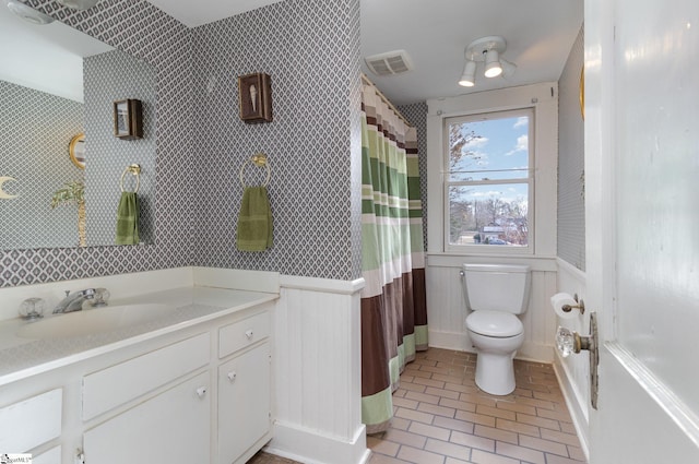 bathroom featuring wooden walls, vanity, and toilet