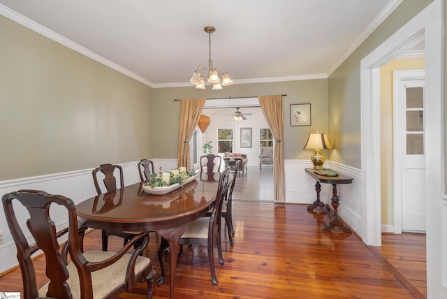 dining area with hardwood / wood-style floors, ceiling fan with notable chandelier, and crown molding