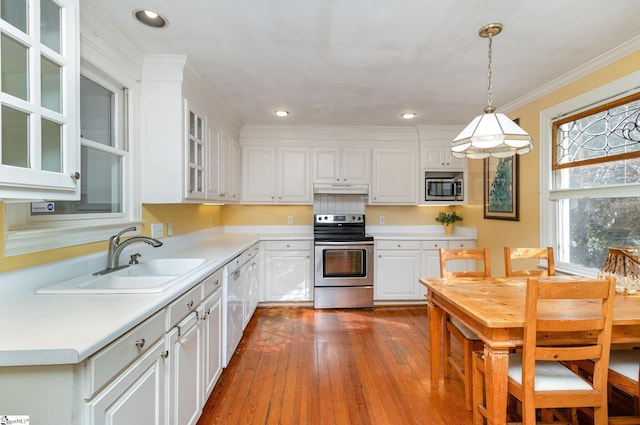 kitchen featuring white cabinets, appliances with stainless steel finishes, hanging light fixtures, and sink