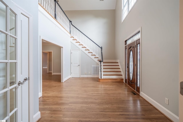 entryway with hardwood / wood-style flooring and a towering ceiling