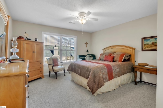 bedroom featuring a textured ceiling, ceiling fan, and light carpet