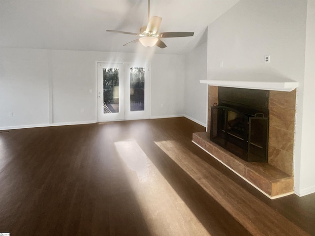 unfurnished living room with ceiling fan, dark wood-type flooring, and a tile fireplace