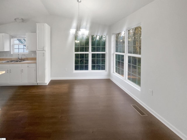 unfurnished dining area featuring dark hardwood / wood-style floors, lofted ceiling, sink, and a chandelier