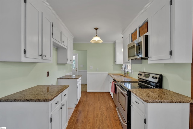 kitchen with appliances with stainless steel finishes, sink, decorative light fixtures, dark stone countertops, and white cabinetry