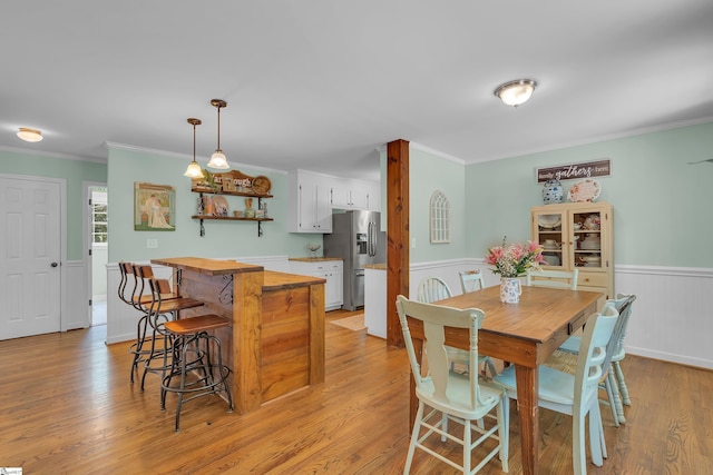 dining space with light hardwood / wood-style floors and ornamental molding