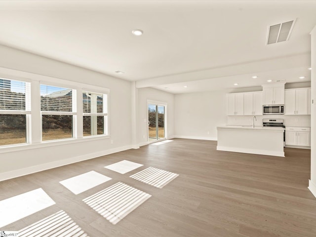 unfurnished living room featuring sink and hardwood / wood-style floors