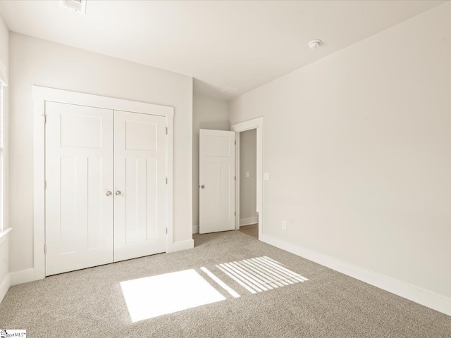 unfurnished bedroom featuring light colored carpet and a closet