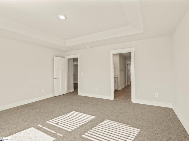 carpeted spare room featuring a raised ceiling