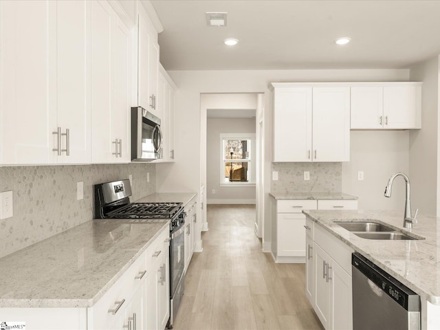 kitchen with white cabinets, sink, light stone counters, and stainless steel appliances