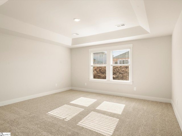 carpeted empty room featuring a tray ceiling