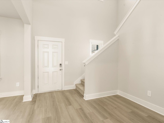 foyer entrance with light hardwood / wood-style flooring and a towering ceiling