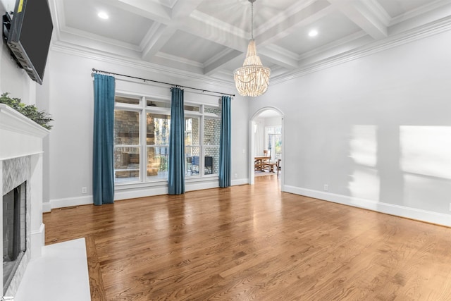 unfurnished living room featuring a high end fireplace, ornamental molding, coffered ceiling, hardwood / wood-style flooring, and a chandelier