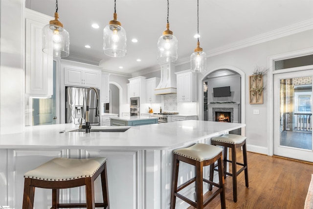 kitchen with a breakfast bar, decorative light fixtures, white cabinets, and premium range hood