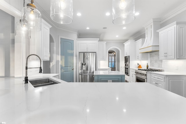 kitchen featuring sink, premium range hood, pendant lighting, white cabinets, and appliances with stainless steel finishes