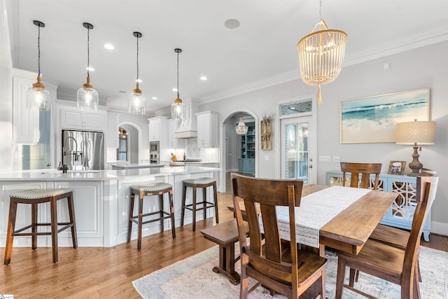 dining space with light hardwood / wood-style flooring, a chandelier, and ornamental molding