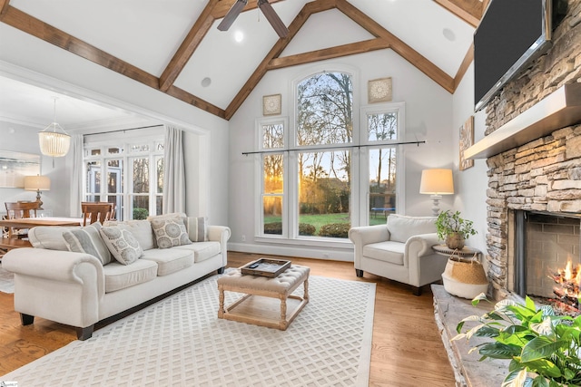 living room featuring ceiling fan with notable chandelier, high vaulted ceiling, beamed ceiling, a fireplace, and hardwood / wood-style floors